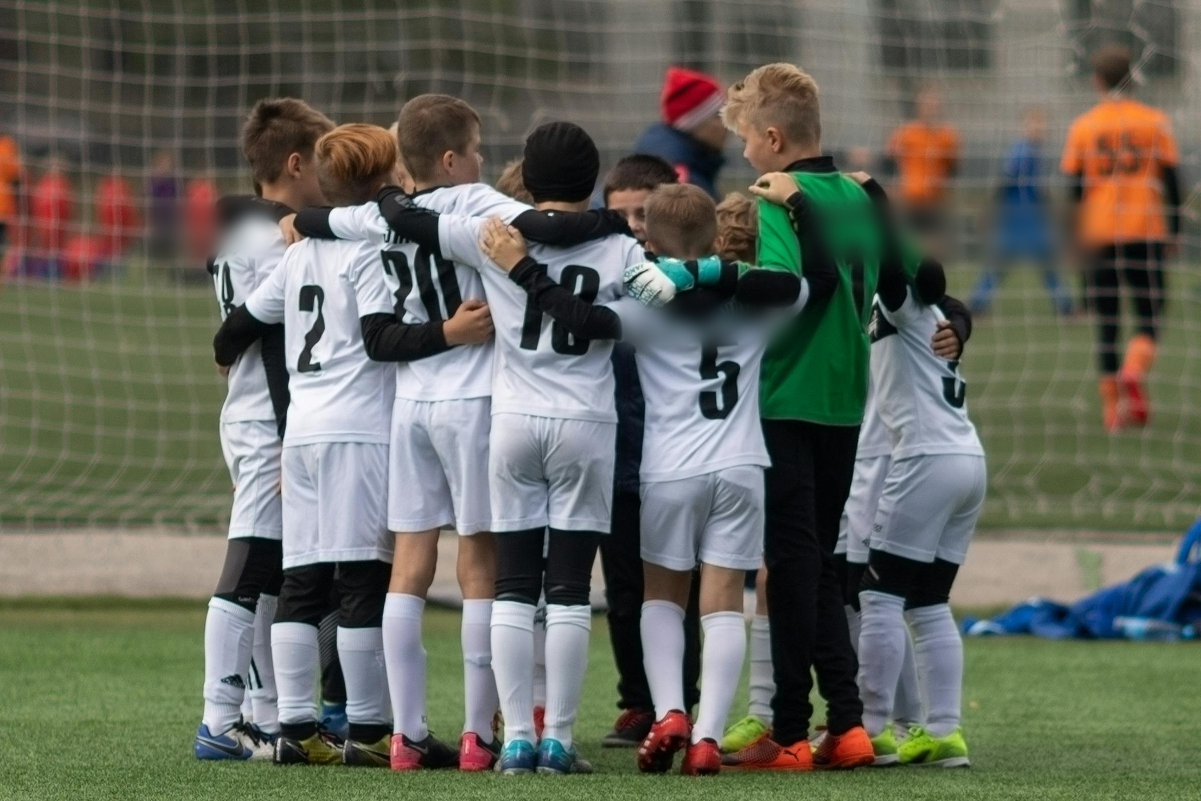 A youth team huddling together on the field